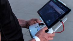 A person operating a UAV using a handheld remote controller and screen